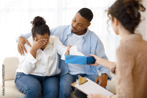 Black man comforting crying wife, couple attend family therapy © Prostock-studio