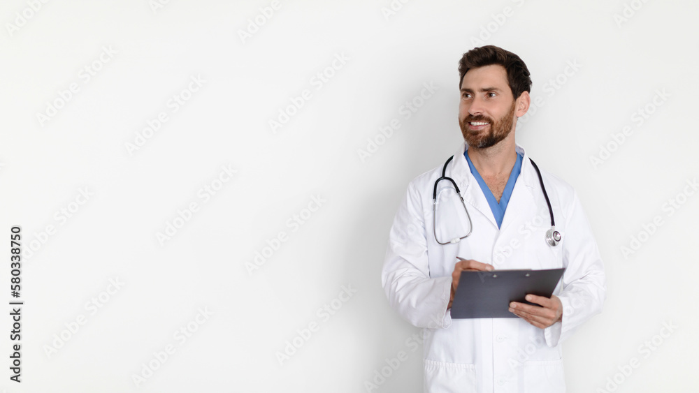 Medical Offer. Handsome male doctor in uniform holding clipboard and looking aside Medical Offer. Handsome male doctor in uniform holding clipboard and looking aside