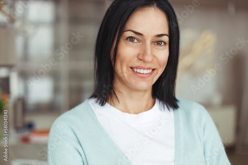 Portrait of successful confident mature female entrepreneur happy and proud of her prosperous small business, standing against blurred home interior looking at camera with confidence Free Download Portrait of successful confident mature female entrepreneur happy and proud of her prosperous small business, standing against blurred home interior looking at camera with confidence - GFXLoad