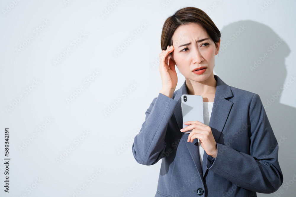 スマートフォンを持ちながら悩んでいる若い女性 ビジネスイメージ スマートフォンを持ちながら悩んでいる若い女性 ビジネスイメージ