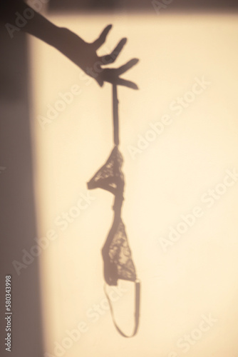 A shadow view of the female lingerie (bra) hanging from the hand 