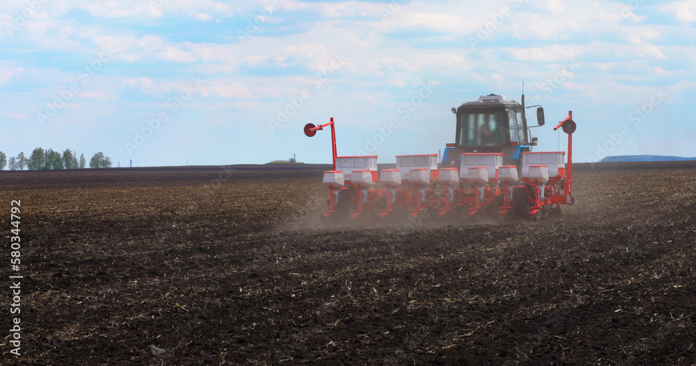 Fototapeta premium Seeding Machine Working in Field on the Farm. Agriculture. Tractor Seeder it Plants Seeds in the Ground. Tillage Equipment. 