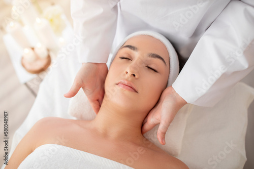 Young indian female enjoying therapeutic neck massage in spa
