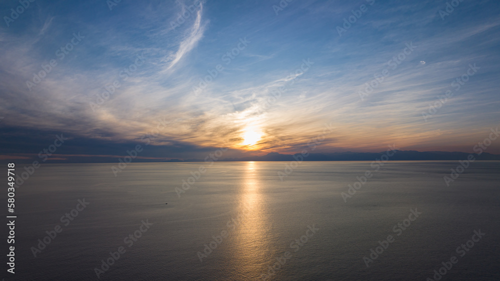 Sunset seascape. The red sun setting among the clouds. blue sky