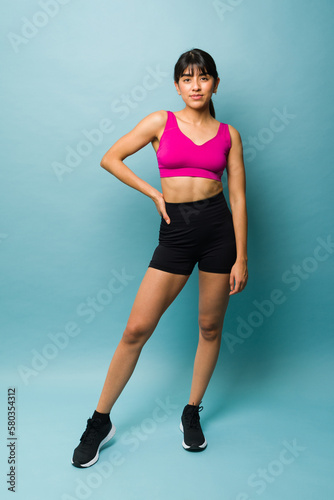 Latin fit young woman in activewear looking happy