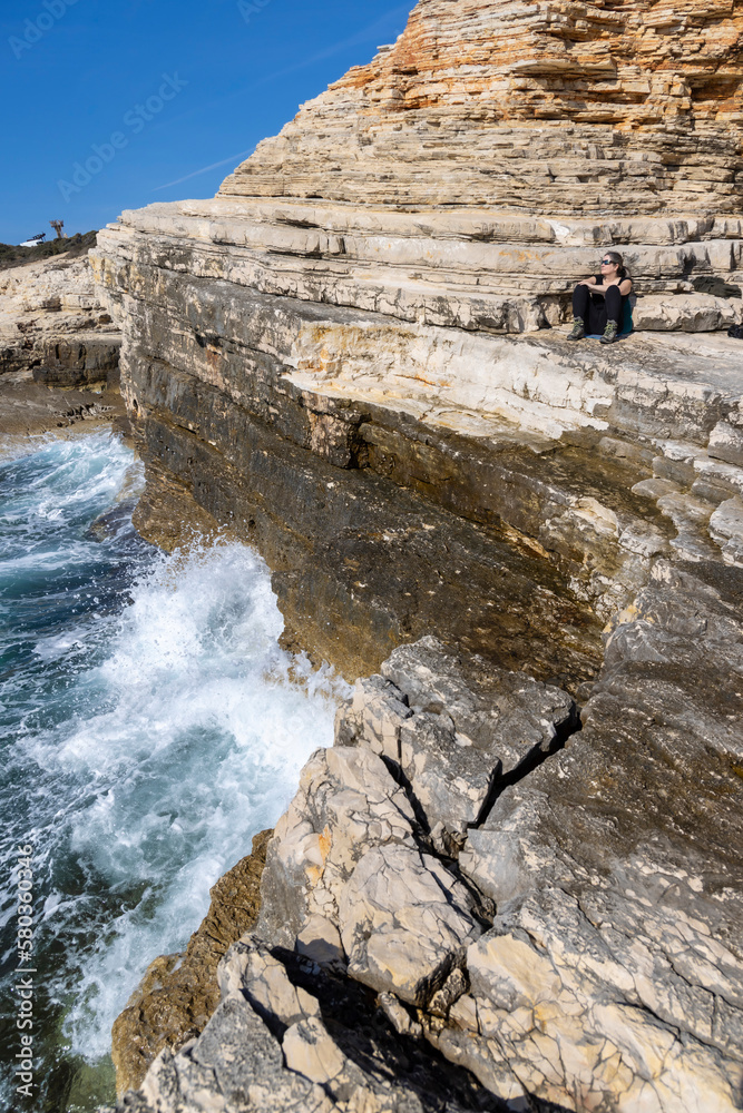woman sitting on the rocks of Cape Kamenjak, a protected natural area on the southern tip of the Istrian peninsula in Croatia, Europe
