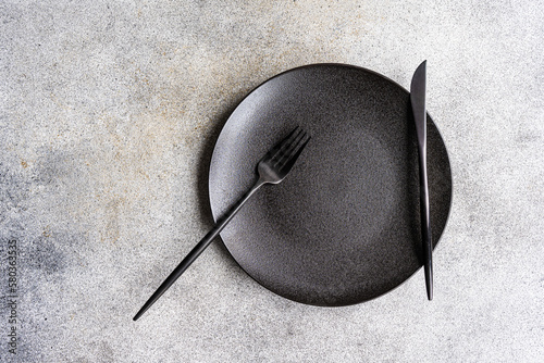 Minimalistic table on a concrete background with a plate a knife and a fork photo
