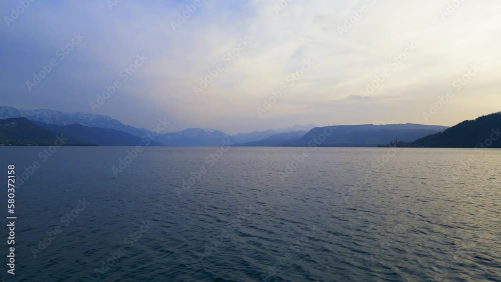 Beautiful low altitude drone view of Lake Attersee, Upper Austria, Europe, on a dark, cloudy, cold early spring day - camera moves rearward Beautiful low altitude drone view of Lake Attersee, Upper Austria, Europe, on a dark, cloudy, cold early spring day - camera moves rearward