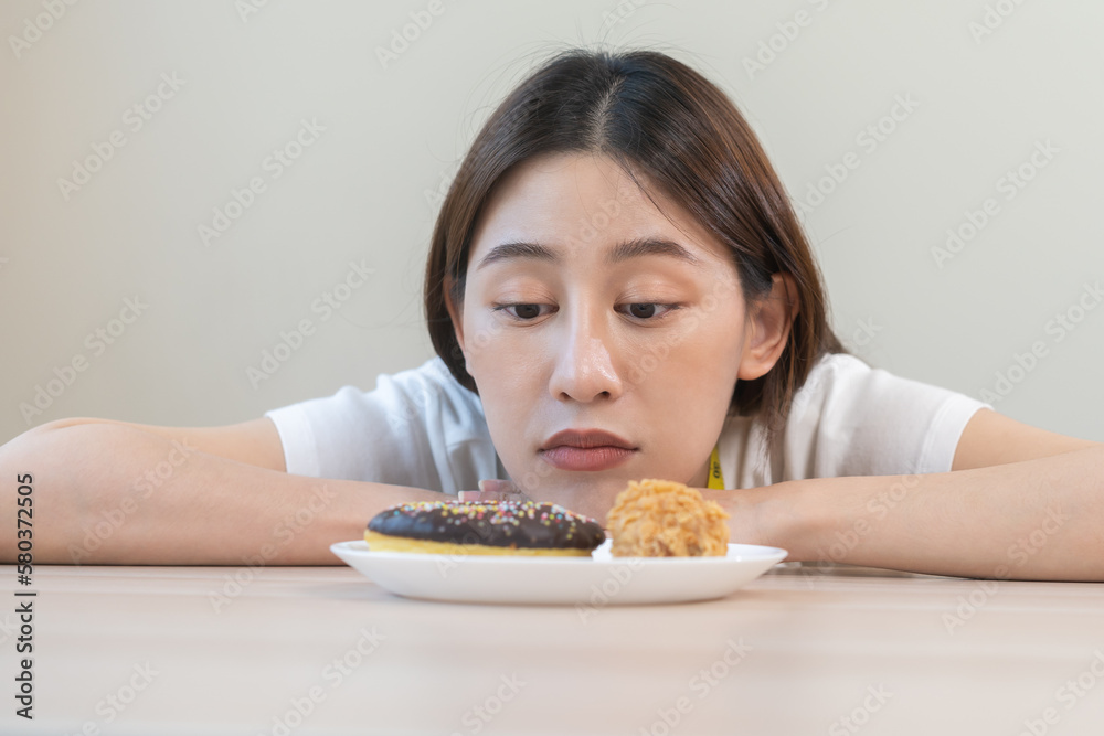 Diet, dieting asian young woman, girl expression face bored, looking at doughnut, bakery and fried chicken, fast food in plate to loss weight. Passion, temptation when hungry restrained to eat. Diet, dieting asian young woman, girl expression face bored, looking at doughnut, bakery and fried chicken, fast food in plate to loss weight. Passion, temptation when hungry restrained to eat.