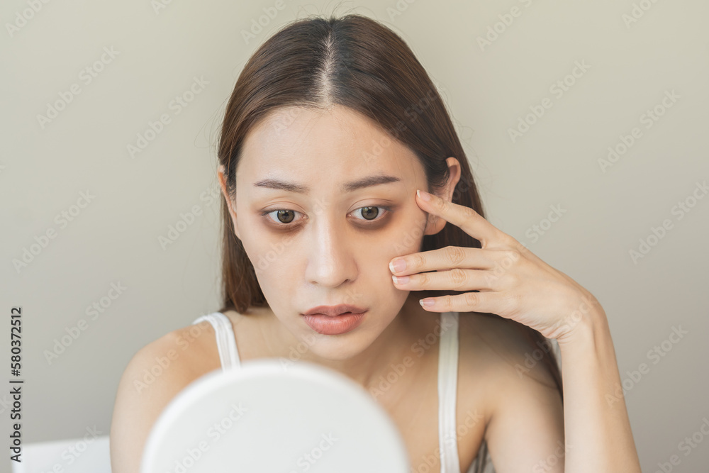 Bored, insomnia asian young woman, girl looking at mirror hand touching under eyes with problem of black circles or panda puffy, swollen and wrinkle on face. Sleepless, sleepy healthcare person. Bored, insomnia asian young woman, girl looking at mirror hand touching under eyes with problem of black circles or panda puffy, swollen and wrinkle on face. Sleepless, sleepy healthcare person.