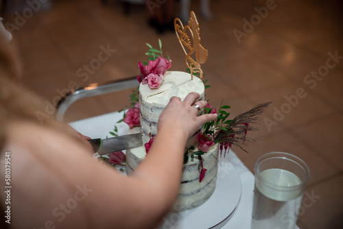 Bride and Groom at Wedding Reception in a restaurant Cutting the Wedding Cake with flowers. High quality photo