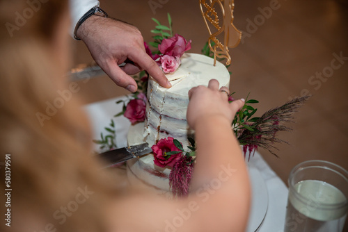 Bride and Groom at Wedding Reception in a restaurant Cutting the Wedding Cake with flowers. High quality photo