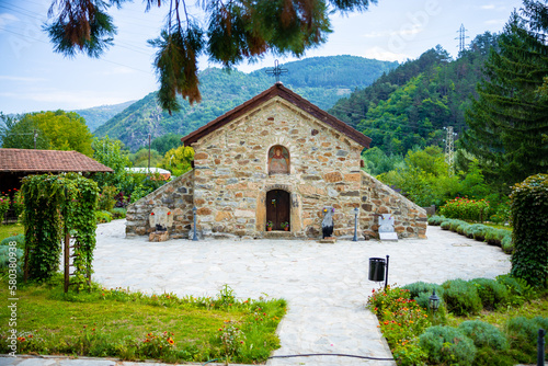 Small beautiful church in Bulgaria in the mountain. Green hills with forests and trees behind it. High quality photo