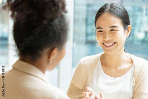 Asian woman talking fluently with her African friend, concept image of good command in foreign language