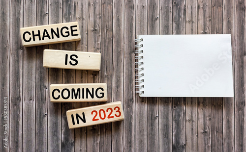 Changes are coming in 2023. Conceptual word Changes that will happen in 2023 on wooden blocks next to a notepad for writing. Beautiful wooden background. Business and change in 2023 concept. 