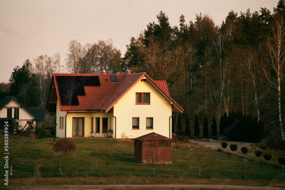 Photovoltaics on the roof of the house. Solar energy source and green energy generation in rural areas. Eco-friendly cottage house. Sustainable future concept Photovoltaics on the roof of the house. Solar energy source and green energy generation in rural areas. Eco-friendly cottage house. Sustainable future concept