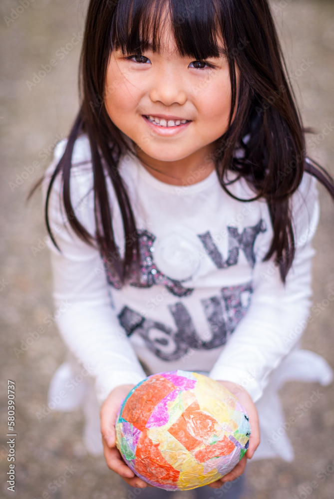 Young asian girl holding colorful paper mache egg in her hand in Easter Young asian girl holding colorful paper mache egg in her hand in Easter