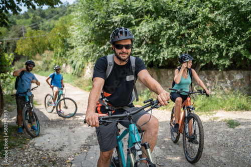 man caucasian male ride electric bicycle e-bike with friends in summer