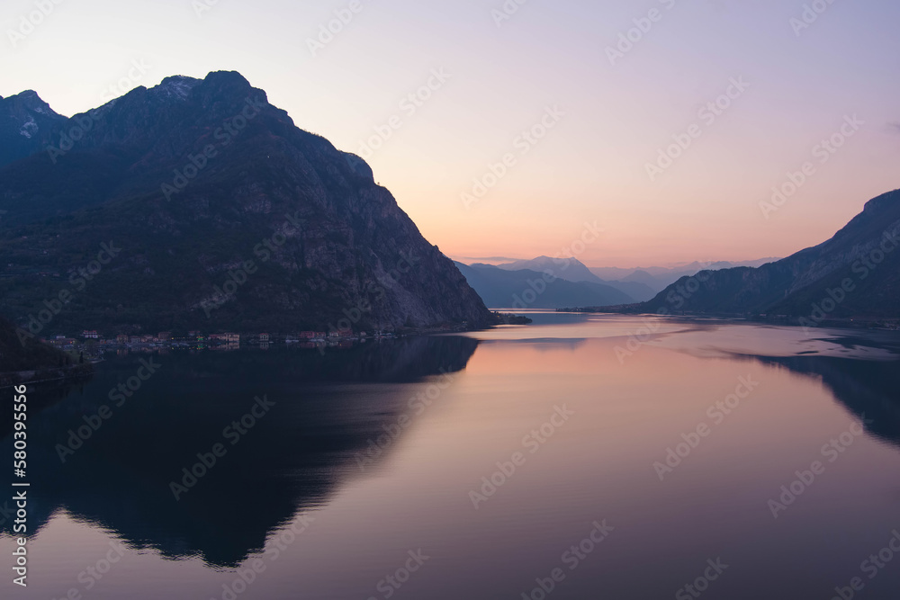 Beautiful aerial view of the famous Como Lake on purple sunset. Mountains reflecting in calm waters of the lake with Alp mountain range on the background. Beautiful aerial view of the famous Como Lake on purple sunset. Mountains reflecting in calm waters of the lake with Alp mountain range on the background.