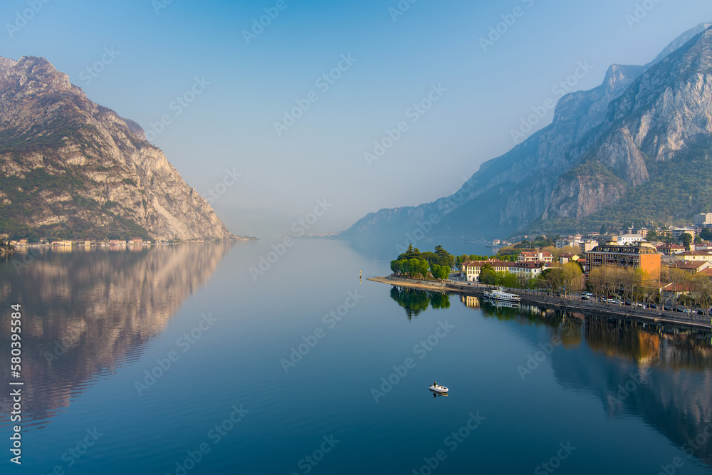 Foggy aerial sunrise cityscape of Lecco town on spring day. Picturesque waterfront of Lecco town located between famous Lake Como and scenic Bergamo Alps mountains.