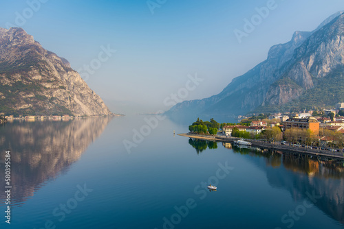 Fototapeta Naklejka Na Ścianę i Meble -  Foggy aerial sunrise cityscape of Lecco town on spring day. Picturesque waterfront of Lecco town located between famous Lake Como and scenic Bergamo Alps mountains.