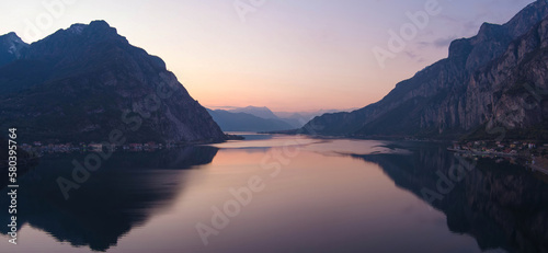 Beautiful aerial view of the famous Como Lake on purple sunset. Mountains reflecting in calm waters of the lake with Alp mountain range on the background.