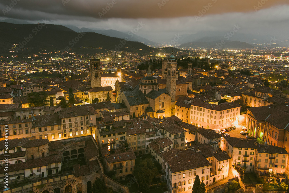 Scenic aerial view of Bergamo city northeast of Milan, on cloudy evening. Flying over Citta Alta, town's upper district encircled by Venetian walls. Bergamo, Italy.