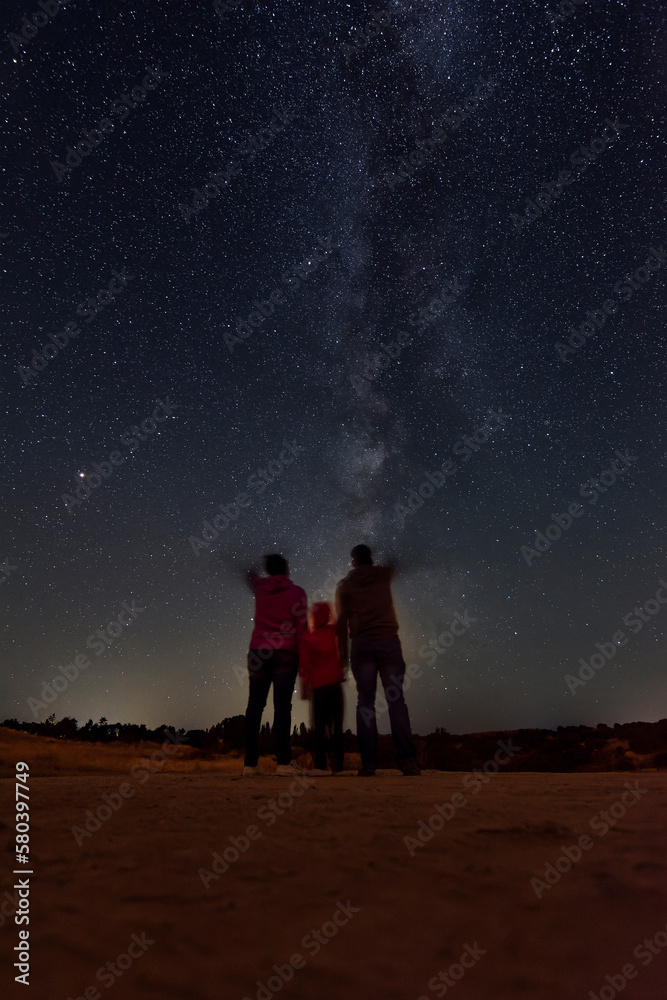 Parents with their daughter watching the milky way Parents with their daughter watching the milky way