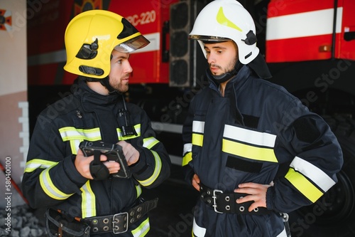 Portrait of two firefighters in fire fighting operation, fireman in protective clothing and helmet using tablet computer in action fighting © Serhii