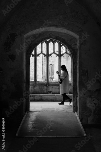 Foto Silhouette of a woman reading while walking in a historic building