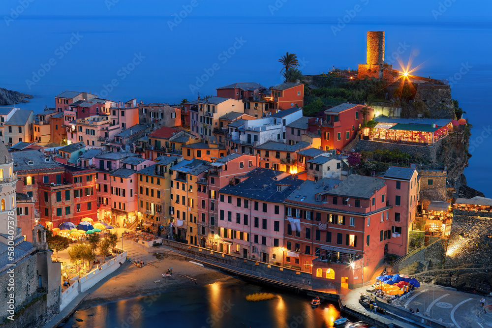 Twiligh view of Picturesque cliff-side village of Vernazza, Cinque Terre, Italy. Famous tourist spot, World Heritage Site with Colorful houses. Blue and orange colors, holiday on Liguria coast, Italy.