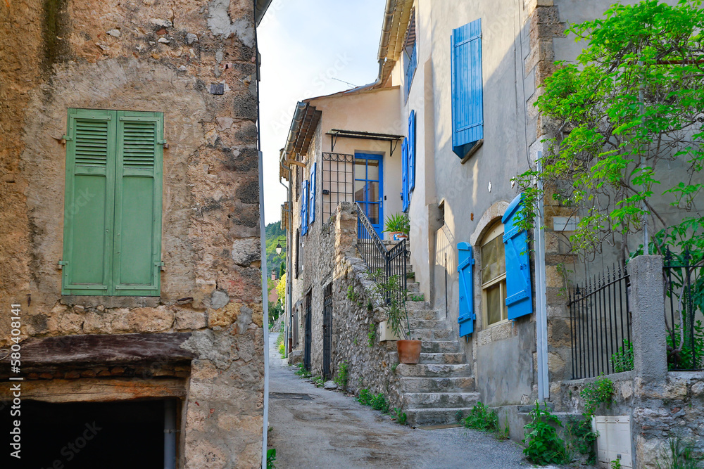 Idyllic french small city narrow streets with bright blue window shutters, stone buildings and rock pavement roads