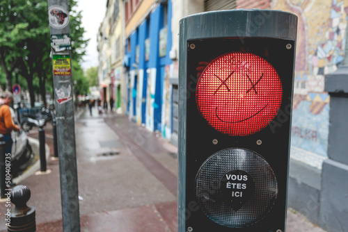 Fototapeta Naklejka Na Ścianę i Meble -  Smiley face drawing on red traffic light with crosses for eyes. Graffiti on traffic light with black marker