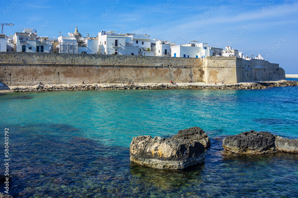 The seaward wall of Monopoli, with an empty bay and rocks

