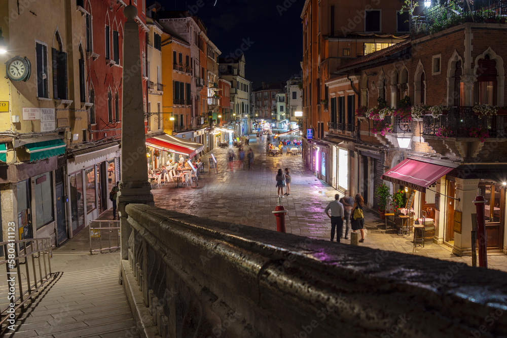 Old houses and narrow street illuminated by night light, Venice, Italy
