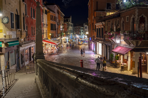 Old houses and narrow street illuminated by night light, Venice, Italy 