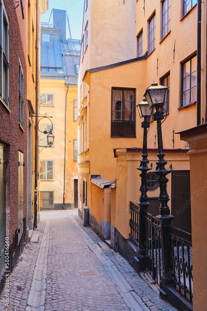 Fototapeta premium Narrow small streets and courtyards of old part of Swedish Stockholm: sunny February tourist day in capital of Scandinavia, Gamla Stan island.
