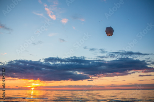 Sky lantern going up the air in from of beautiful sun set over the sea at beach
