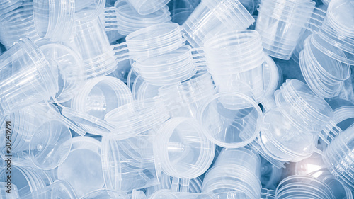 A lot of new transparent plastic glasses as a background in a blue tone