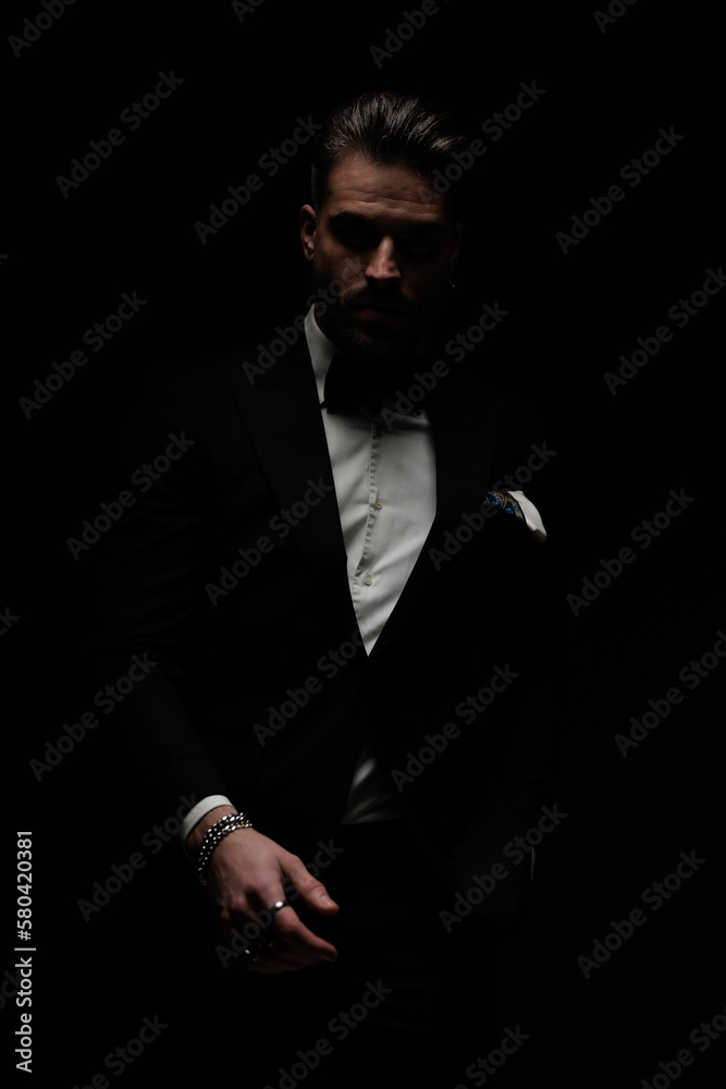 bearded young man in black tuxedo posing in a mysterious way bearded young man in black tuxedo posing in a mysterious way