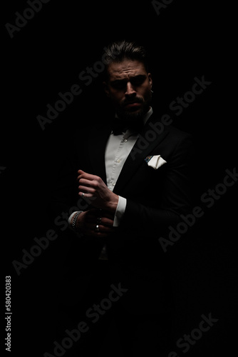 Fototapeta mysterious sexy man with beard looking away and fixing sleeves