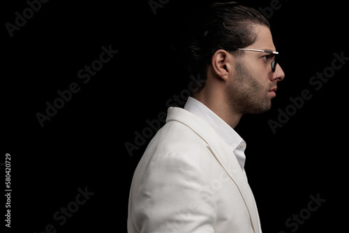 side view of handsome young man with glasses frowning and looking to side