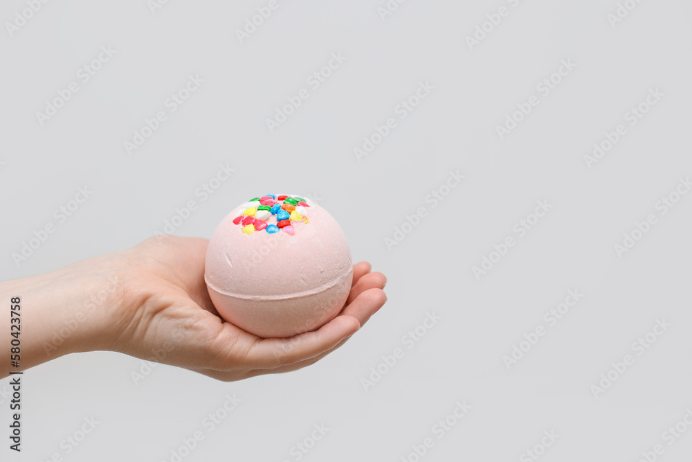 Woman with bath bomb on light background