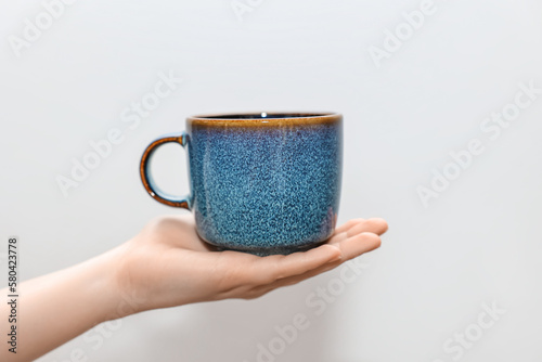 Woman holding blue cup on light background