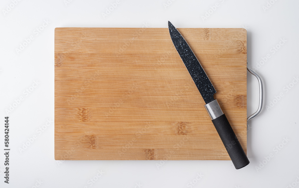 Wooden cutting board and a knife on a white background. Kitchen utensils. Space for text. 