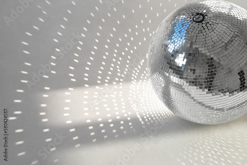 A mirror ball with sunbeams on a photo studio cyclorama. Natural light with shadows. Space for text. 