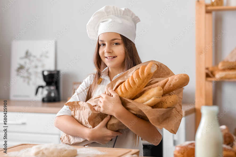 Little baker with tasty baguettes in kitchen - obrazy, fototapety, plakaty 