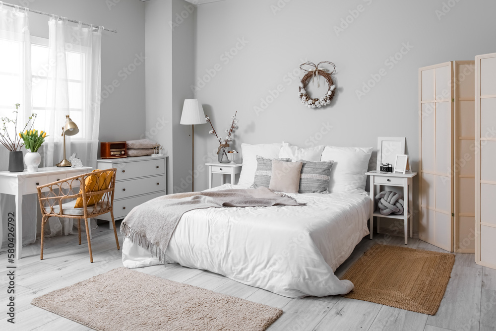 Obraz premium Interior of light bedroom with Easter wreath, cotton flowers and tables