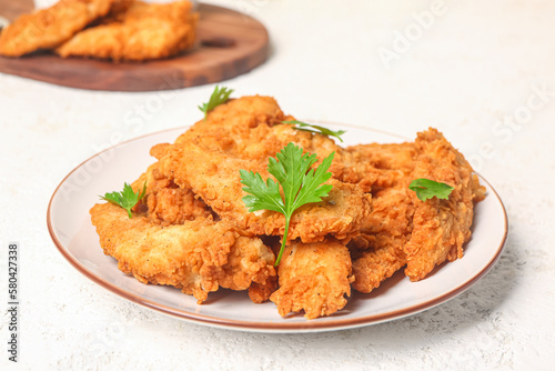 Plate of tasty nuggets with parsley on light background