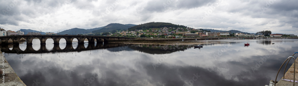 Vista panorámica de la ria de Vicedo en Lugo con vistas del viejo puente y nubes reflejadas en el agua del río, en Galicia, verano de 2021 Vista panorámica de la ria de Vicedo en Lugo con vistas del viejo puente y nubes reflejadas en el agua del río, en Galicia, verano de 2021